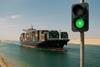 container ship in canal with traffic light showing green