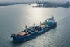 Pacific Basin ship at sea with port and cranes in background