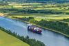 {d8a94538-d4cf-40af-a551-36d9deba62cb}_ET_Ind_475_Vessel_passing_through_canal_in_green_landscape