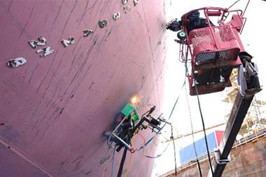 A worker using the InfraLaser rust and coating removal system on a ship's hull