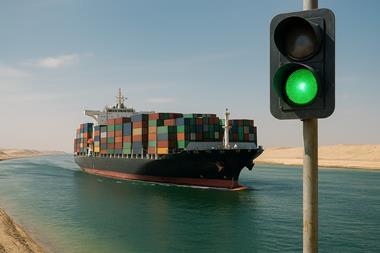 container ship in canal with traffic light showing green