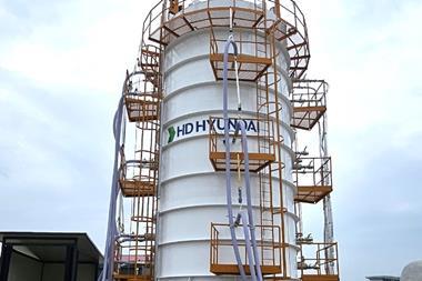 Workers in white hard hats in front of an HD KSOE LH2 vacuum tank