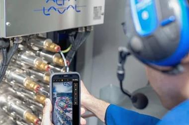 An Alfa Laval engineer working on some equipment and looking at a smart phone screen