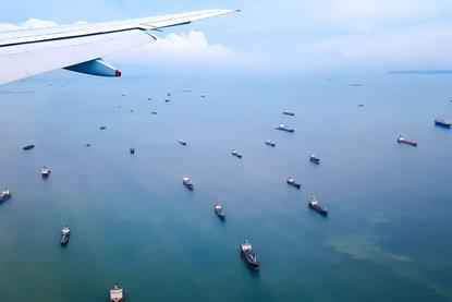 aircraft wing over ocean with a fleet of ships