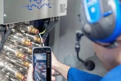 An Alfa Laval engineer working on some equipment and looking at a smart phone screen