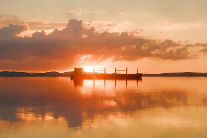 A ship silhouetted against a salmon pink sunset