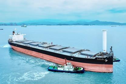 Bulk carrier Yodohime at sea featuring a single Rotor Sail at its bow and a tugboat alongside