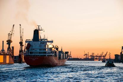 Container ship coming into port with cranes in the background