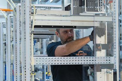 The image shows a technician in the process of assembling The Switch DC-Hub cabinets.