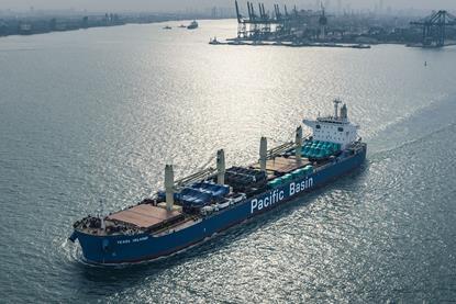 Pacific Basin ship at sea with port and cranes in background