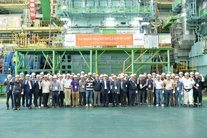 The image shows a group shot of WinGD and Hanwha Group employees in front of the LNG carrier engine