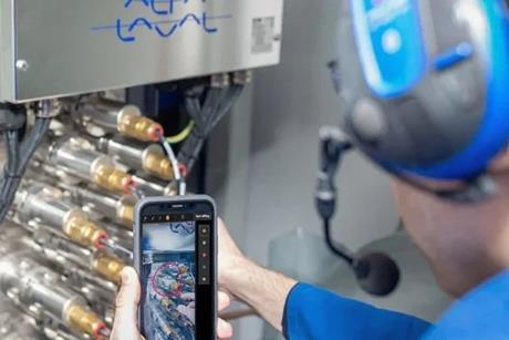 An Alfa Laval engineer working on some equipment and looking at a smart phone screen
