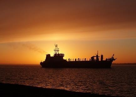A ship in shadow at sunset