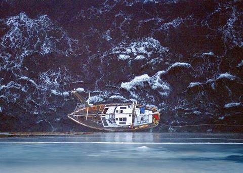 A small boat is dwarfed by the side of the ship attending its rescue